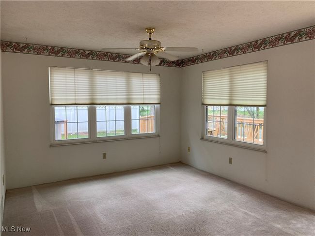 Spare room featuring healthy amount of natural light, light carpet, ceiling fan, and a textured ceiling | Image 25