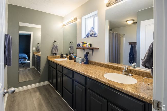 Bathroom featuring baseboards, wood finished floors, a sink, and double vanity | Image 12