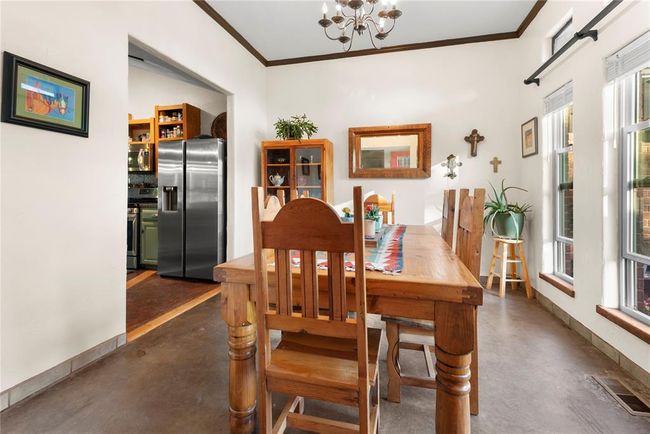 Dining space with visible vents, ornamental molding, finished concrete floors, and a notable chandelier | Image 7