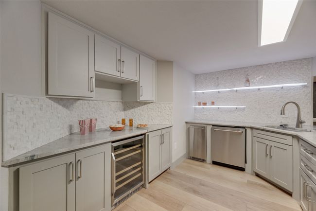 Kitchen with beverage cooler, stainless steel dishwasher, a sink, and decorative backsplash | Image 26