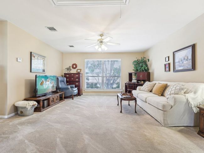 Living room with attic access, carpet floors, ceiling fan, and baseboards | Image 21