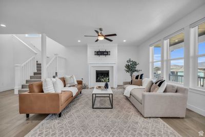 Living room with a brick fireplace, light hardwood / wood-style floors, and ceiling fan | Image 2