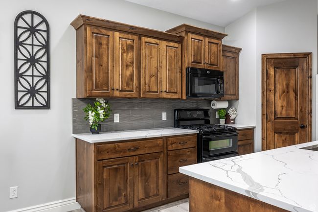 Kitchen with backsplash, black appliances, and light stone countertops | Image 9