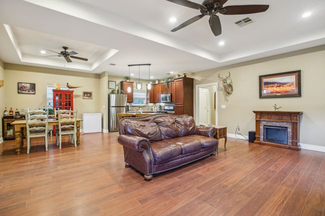 Living room featuring ceiling fan, a fireplace, a tray ceiling, and light wood-type flooring | Image 11