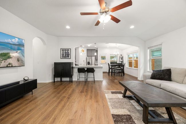 Living area with arched walkways, wood finished floors, recessed lighting, ceiling fan, and a chandelier | Image 5