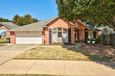 Ranch-style home featuring a front yard and a garage | Image 1