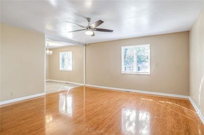 Empty room featuring ceiling fan with notable chandelier, light hardwood / wood-style floors, and plenty of natural light | Image 2