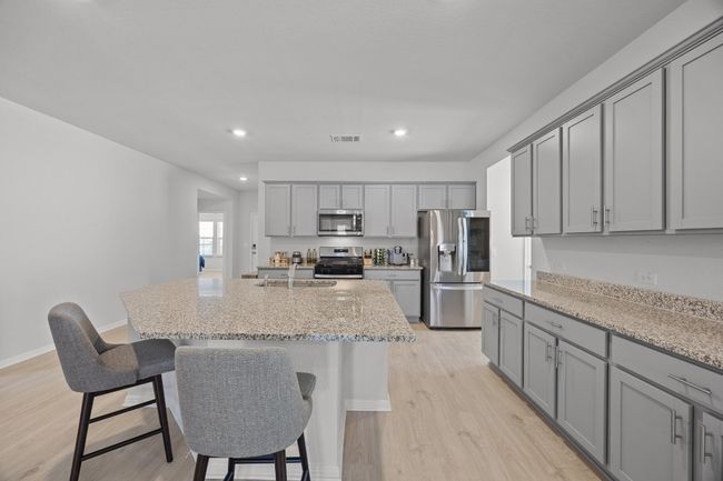 Kitchen featuring gray cabinetry, a large sink, light wood-look floors, and appliances with stainless steel finishes | Image 8