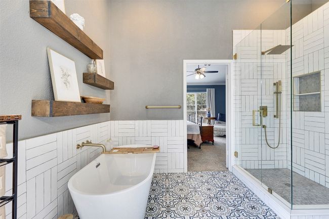 Full bath featuring a stall shower, ensuite bathroom, tile patterned flooring, a freestanding tub, and a ceiling fan | Image 22