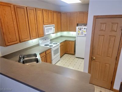 Kitchen featuring kitchen peninsula, sink, and white appliances | Image 2