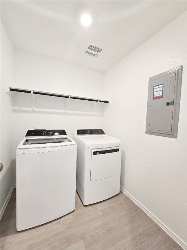 Laundry area with electric panel, washing machine and dryer, light wood-type flooring, and baseboards | Image 26