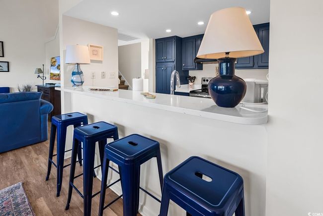 Kitchen with wood finished floors, a breakfast bar area, a sink, stainless steel range with electric cooktop, and blue cabinetry | Image 11
