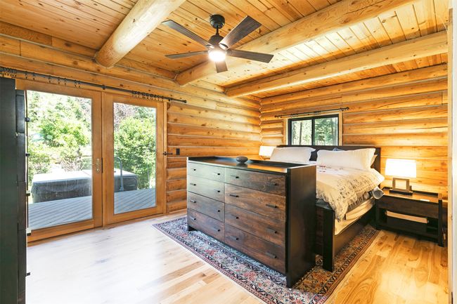 Master Bedroom featuring wood ceiling with exposed beams, wood finished floors, access to exterior, and rustic walls | Image 19