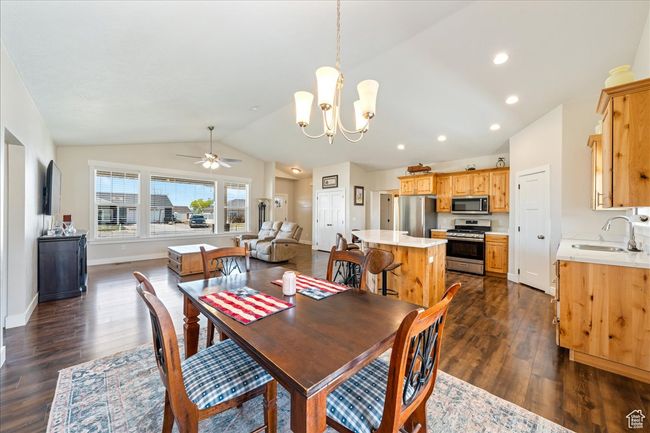 Dining area featuring vaulted ceiling, ceiling fan with notable chandelier, dark wood finished floors, baseboards, and recessed lighting | Image 18