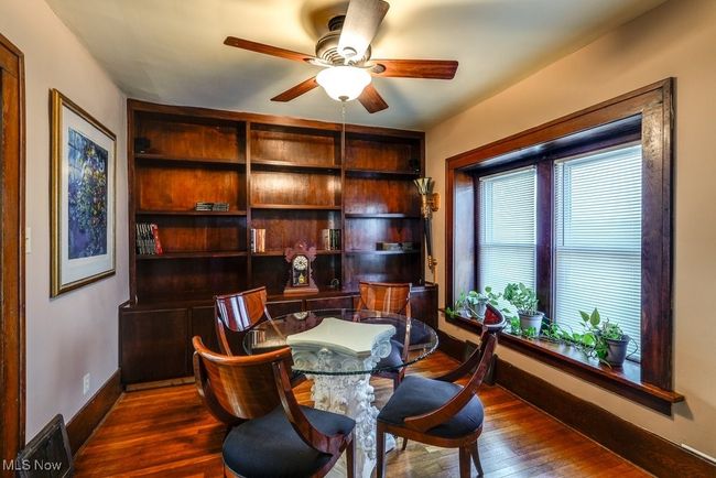 Sitting room/dining room with baseboards, a ceiling fan and dark wood-type flooring and bookcases | Image 11