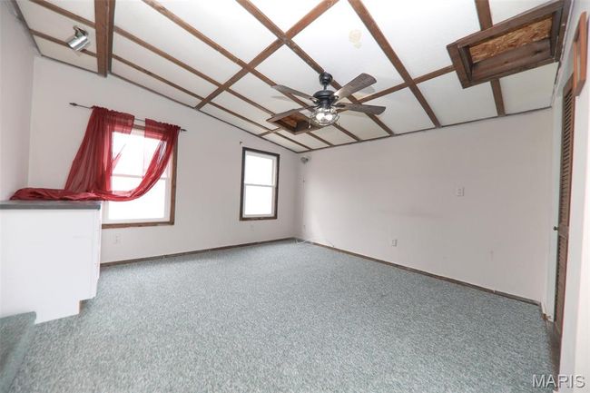 Empty room with baseboards, carpet floors, ceiling fan, and vaulted ceiling | Image 18