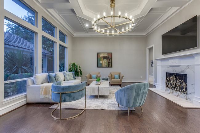 The large family room has a beautiful marble fireplace, and a beautifully designed ceiling treatment with a wagonwheel-style chandelier. | Image 12