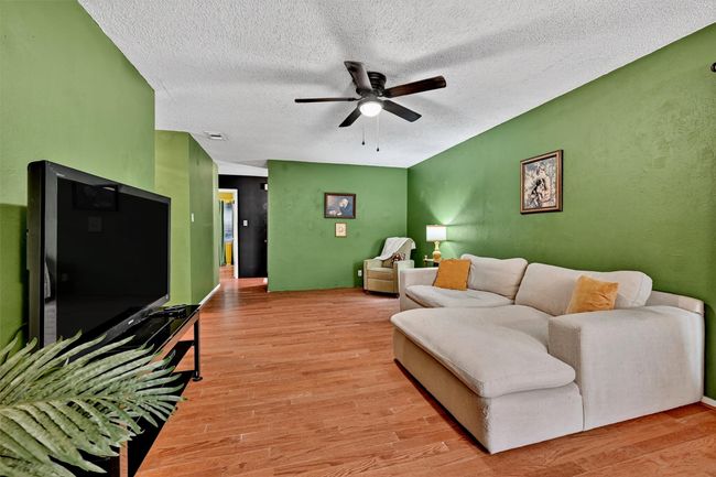Living room featuring a ceiling fan, light wood finished floors, and a textured ceiling | Image 7