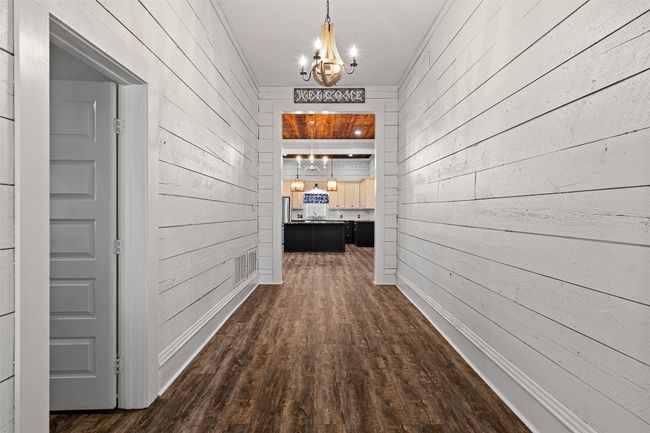 Hall featuring a chandelier, dark wood finished floors, visible vents, and wood walls | Image 5