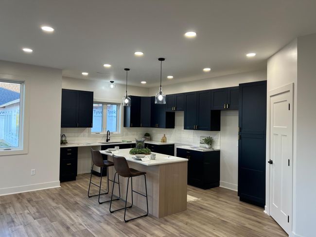 Cooks kitchen with dark navy cabinets, quartz countertops and natural wood toned island | Image 4