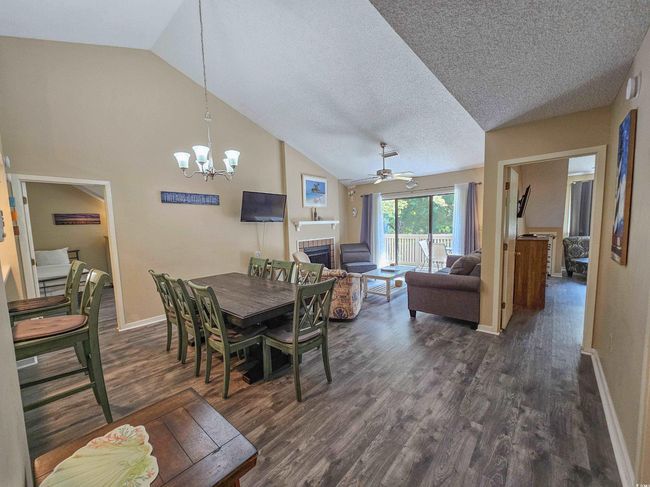 Dining room with vaulted ceiling, dark wood finished floors, baseboards, a chandelier, and ceiling fan | Image 17