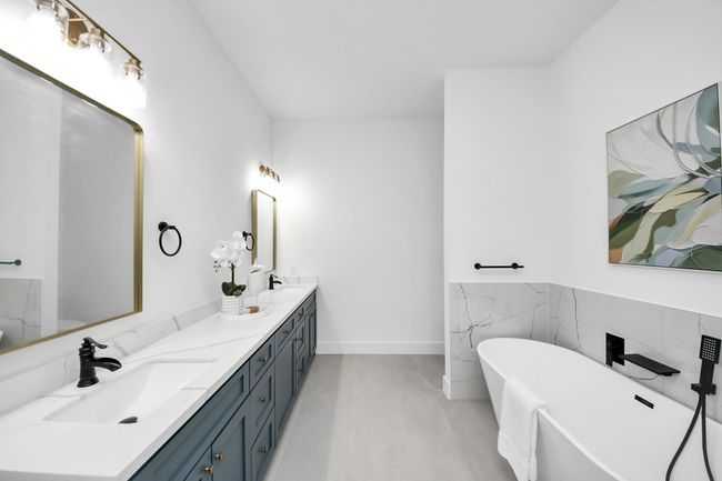 The primary bathroom features dual sinks, light countertops, freestanding tub, and separate shower. | Image 15