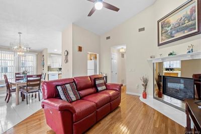 Living room featuring vaulted ceiling, light hardwood / wood-style flooring, and ceiling fan with notable chandelier | Image 1