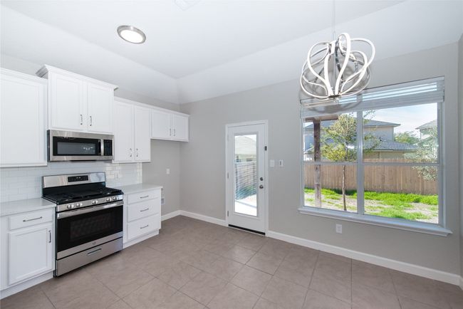 Large open kitchen/dining area, stainless appliances, gas range, OTR microwave and quartz countertops. Back door leads to covered back patio and private back yard. | Image 7