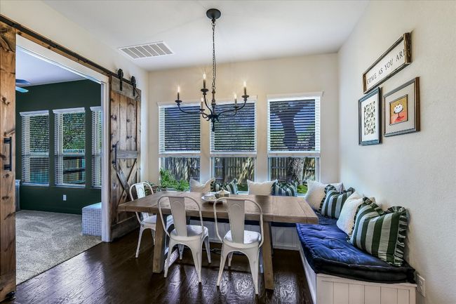 Dining space featuring wood finished floors, a notable chandelier, visible vents, and a barn door | Image 11