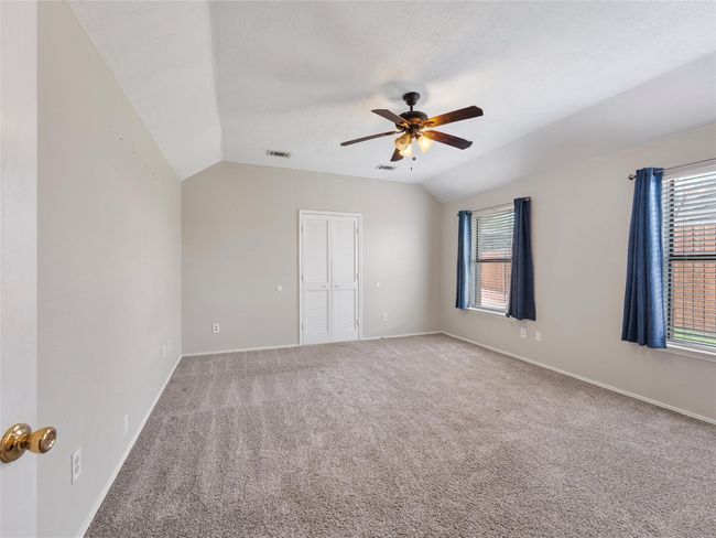 Unfurnished bedroom with lofted ceiling, carpet, multiple windows, ceiling fan, and a closet | Image 15