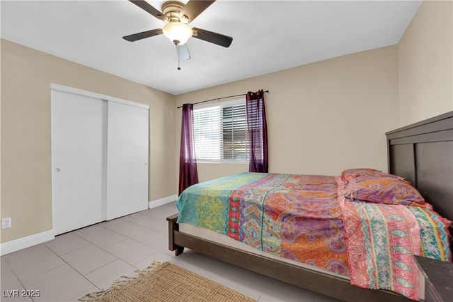 Tiled bedroom with baseboards, ceiling fan, and a closet | Image 11