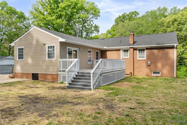 Rear view of property featuring a wooden deck, a chimney, crawl space, a yard, and brick siding | Image 37