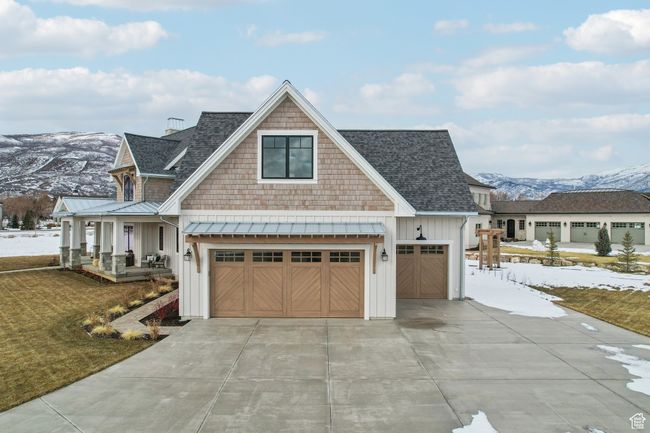 View of front of property with covered porch, board and batten siding, a standing seam roof, a mountain view, and driveway | Image 54