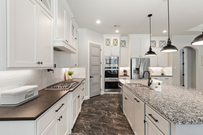 Kitchen featuring white cabinets, glass insert cabinets, appliances with stainless steel finishes, and a sink | Image 11