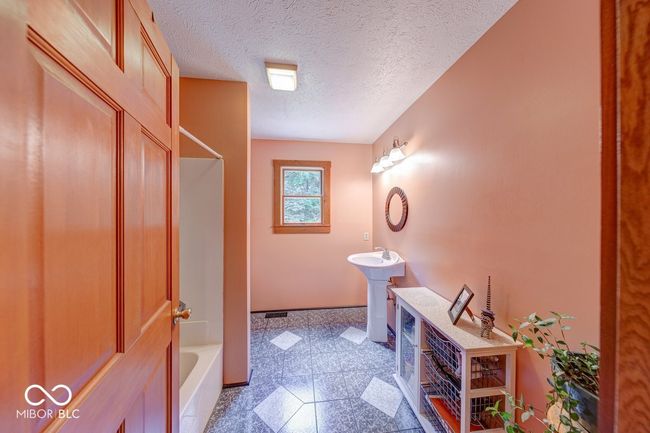 bathroom featuring granite floors, tub / shower combination, and a textured ceiling | Image 38