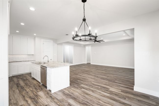 Kitchen featuring pendant lighting, white cabinets, a center island with sink, sink, and light stone countertops | Image 18
