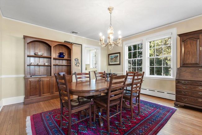 Dining area featuring light wood finished floors, visible vents, a baseboard heating unit, ornamental molding, and baseboards | Image 13