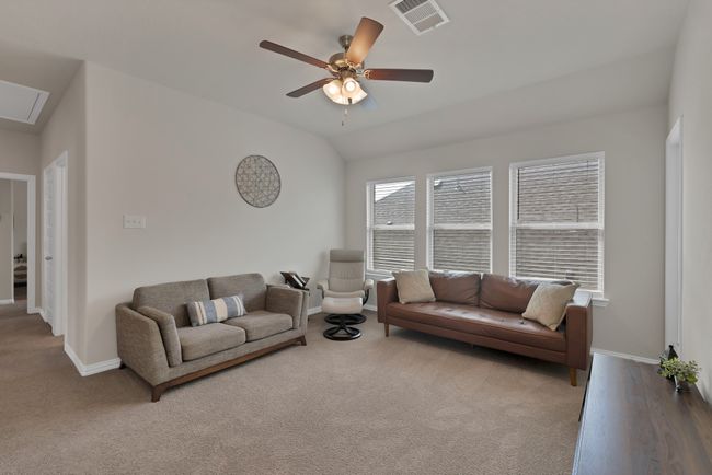 Carpeted living room featuring baseboards, visible vents, vaulted ceiling, and a ceiling fan | Image 26