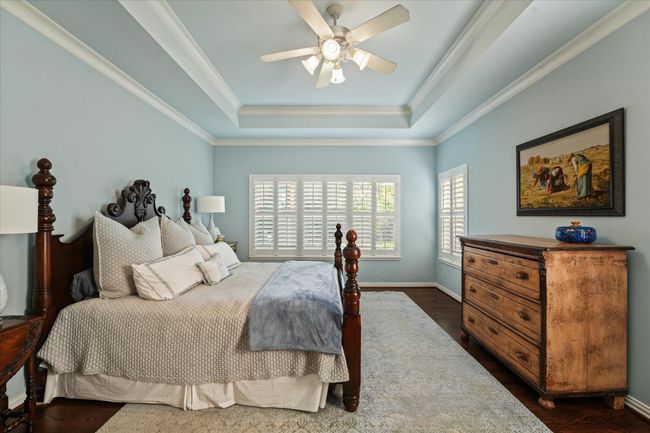 Bedroom with a tray ceiling, crown molding, dark wood-style floors, and ceiling fan | Image 21