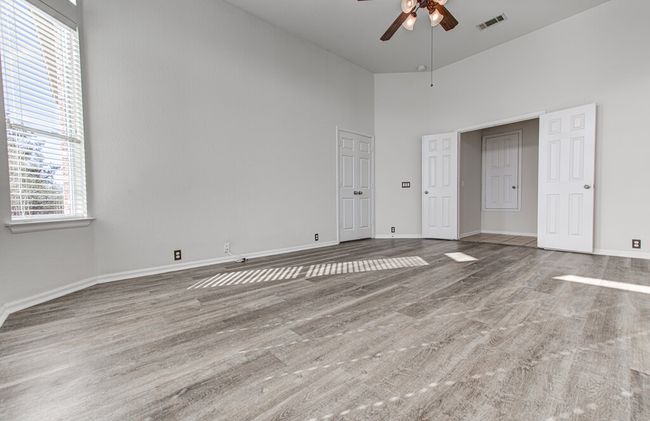Unfurnished bedroom featuring visible vents, multiple windows, wood finished floors, and a towering ceiling | Image 20
