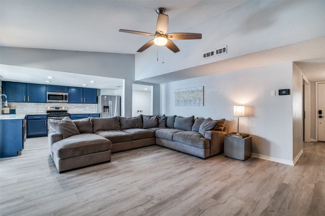 Living room featuring high vaulted ceiling, light wood finished floors, ceiling fan, and baseboards | Image 5