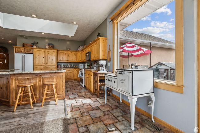 Kitchen featuring baseboards, visible vents, high end appliances, a skylight, and light stone countertops | Image 15