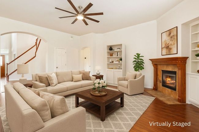 Living room featuring arched walkways, ceiling fan, light wood-style floors, built in shelves, and crown molding | Image 10