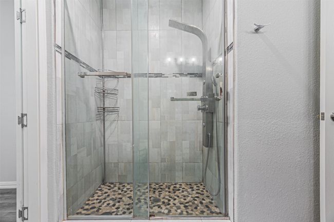 Bathroom featuring a shower stall and a textured wall | Image 16
