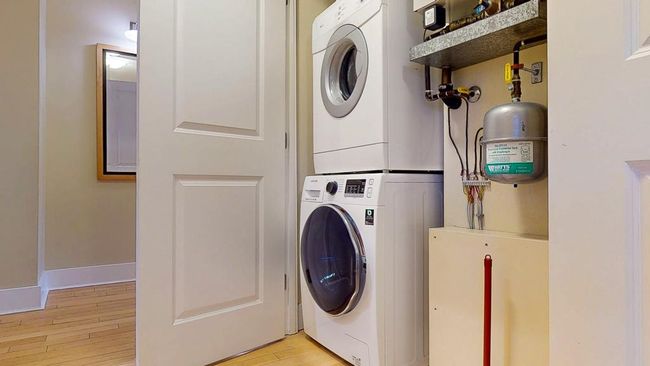 Laundry area with baseboards, stacked washer and dryer, light wood-style. | Image 31