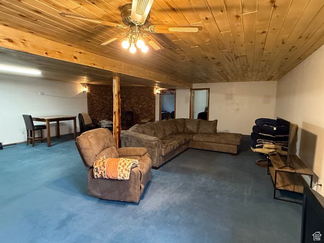 Living room with a large fireplace, wood ceiling, ceiling fan, and carpet floors | Image 14