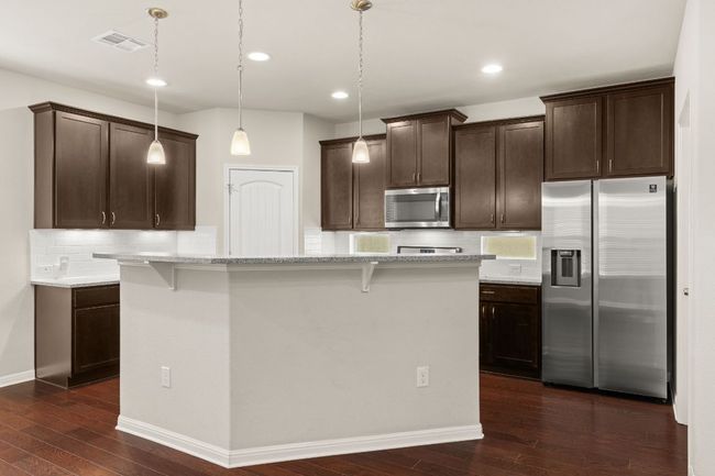 Kitchen featuring stainless steel appliances, dark wood-type flooring, dark brown cabinets, decorative backsplash, and recessed lighting | Image 5