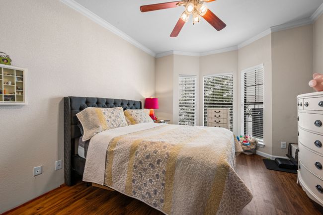 Bedroom featuring wood finished floors, crown molding, and a ceiling fan | Image 18