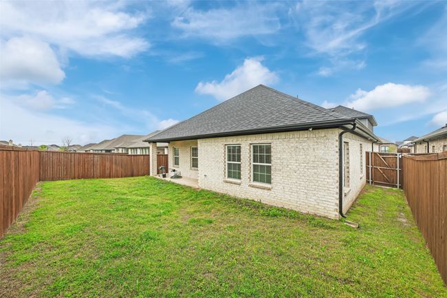 Back of house with a yard, brick siding, a fenced backyard, and a shingled roof | Image 31