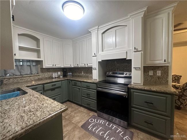 Kitchen with white cabinetry, sink, light tile patterned floors, tasteful backsplash, and stainless steel range with electric cooktop | Image 5